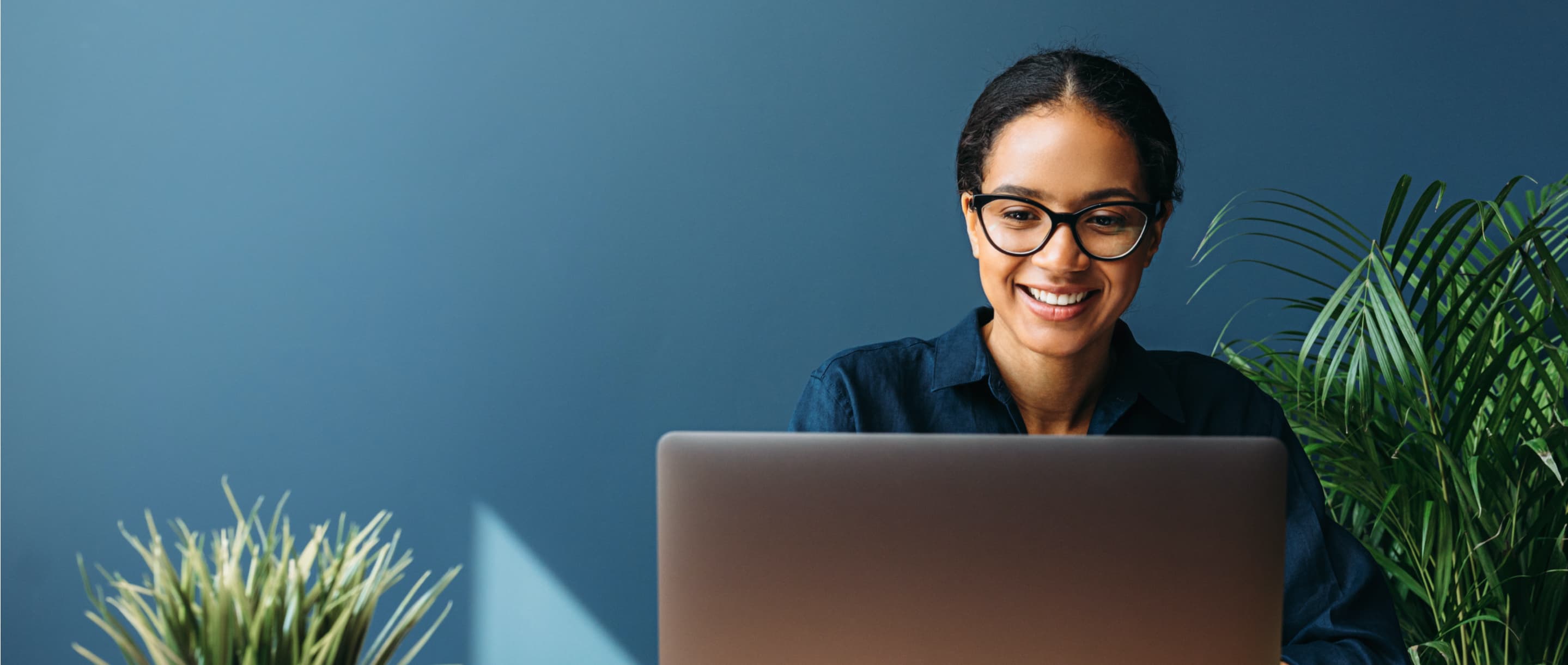 Woman with glasses smiling at laptop